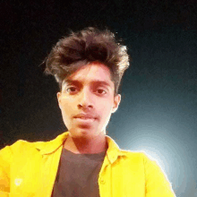 a young man wearing a yellow jacket is taking a selfie .