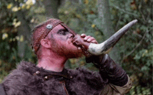 a man in a fur coat is drinking from a horn .