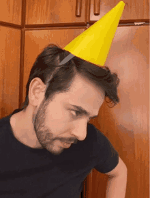 a man wearing a yellow party hat with a knife in his hair