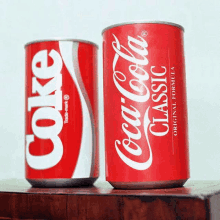 two cans of coca cola sit on a table