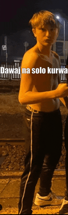 a man without a shirt is standing in front of a railroad track at night