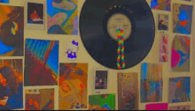 a record is hanging on a wall surrounded by paintings .