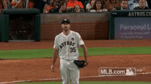 a baseball player is standing on the field holding a glove .