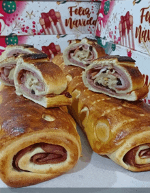 a few rolls of bread are sitting on a table in front of a box with feliz navidad written on it