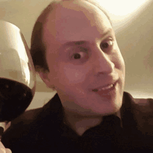 a man is holding a glass of red wine and making a funny face