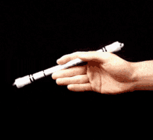 a person 's hand is holding a white object with a black background