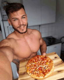 a shirtless man holding a pizza on a wooden cutting board