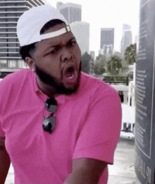 a man wearing a pink shirt and a white hat is making a face