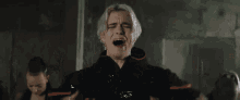 a man in a black jacket is crying with his mouth open .