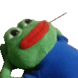 a green stuffed frog wearing a blue shirt and a red mouth is holding a stick in its mouth .