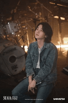 a young man is sitting on a stage in front of a drum set .