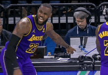 a basketball player wearing a purple lakers jersey is standing on the court