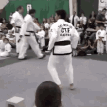 a man in a taekwondo uniform is kicking another man in the face .