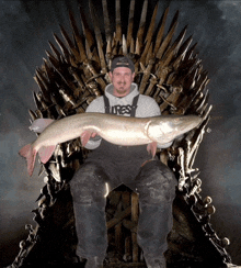 a man is sitting on a throne holding a large fish and wearing a shirt that says ures