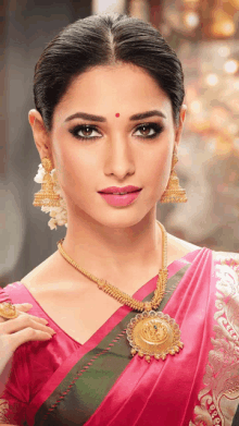 a woman wearing a pink saree and gold jewelry