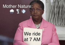 a woman in a pink jacket is holding a sign that says we ride at 7am