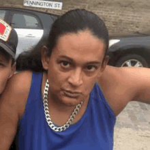 a woman wearing a blue tank top and a silver chain around her neck is standing next to a man .