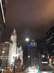 a city street at night with a clock tower and a building that says ' bank of america ' on it