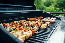 a grill filled with meats and vegetables including skewers and sausages