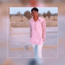 a young man wearing sunglasses and a pink shirt stands in front of a field