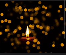 a red candle is lit in the dark with yellow lights behind it