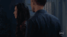 a man and a woman are standing next to each other in a dark room with abc written on the bottom of the screen