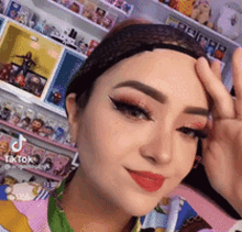 a woman wearing a headband is giving a peace sign while standing in front of a shelf filled with figurines .