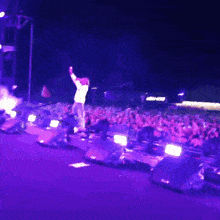 a man stands on a stage in front of a crowd with purple lights and a sign that says ski doo on it