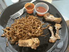 a plate of food with noodles chicken and sauce