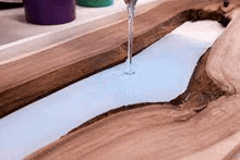 a piece of wood is being poured into a sink with water coming out of it .