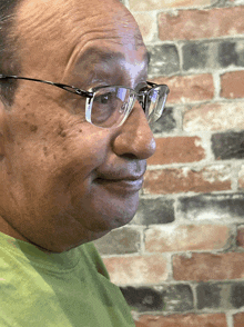 a man wearing glasses and a green shirt is smiling