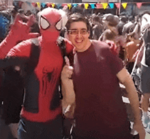 a man in a spiderman costume is posing for a picture with a man in a red shirt