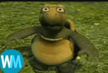 a cartoon turtle is standing on top of a grass covered field .