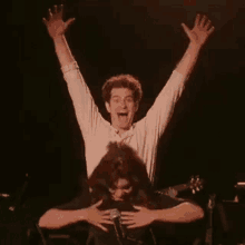 a man is sitting on a woman 's shoulders on a stage with his arms in the air .