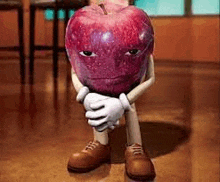 a cartoon apple with arms and legs is sitting on the floor with his hands folded .