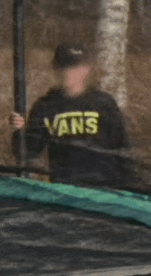 a person wearing a black vans sweatshirt is holding a pole .