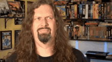 a man with long hair and a beard is standing in front of a shelf full of star wars books