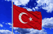 a red and white flag with a crescent moon and star is flying in the wind .