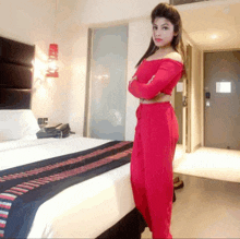 a woman in a red outfit stands next to a bed