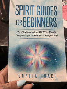 a book titled spirit guides for beginners is held in someone 's hand