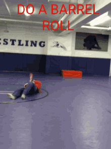 a person laying on the floor in a wrestling gym with the words do a barrel roll written on the wall