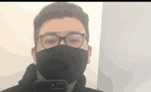 a man wearing glasses and a black face mask takes a selfie