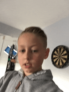 a young boy is standing in front of a dart board that says stryker on it