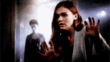 a woman is standing in a dark room with her hands outstretched .