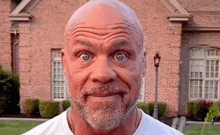 a man with a beard is making a funny face in front of a brick house .