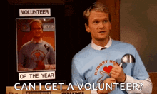 a man is standing in front of a sign that says volunteer of the year and holding a magnifying glass .