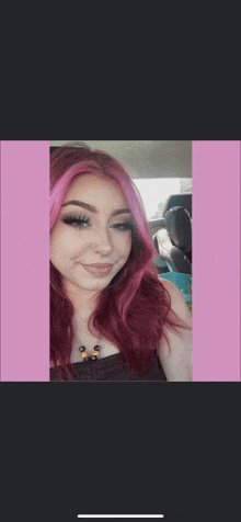 a woman with red hair and pink streaks is sitting in a car