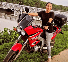 a woman stands next to a red motorcycle that says yamaha on it