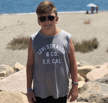 a boy wearing sunglasses and a tank top that says levi strauss and co. s.f. cal