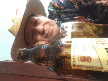 a man wearing a cowboy hat is laying next to a bottle of beer